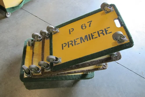 Yellow four-wheel Premiere furniture dollies stacked on a concrete floor